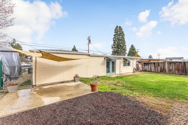 rear view of property with a fenced backyard, concrete block siding, a yard, french doors, and a patio area