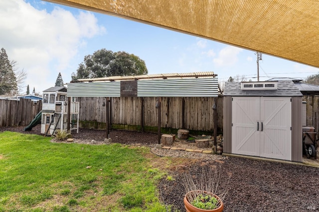 view of yard featuring an outbuilding, a playground, a fenced backyard, and a shed