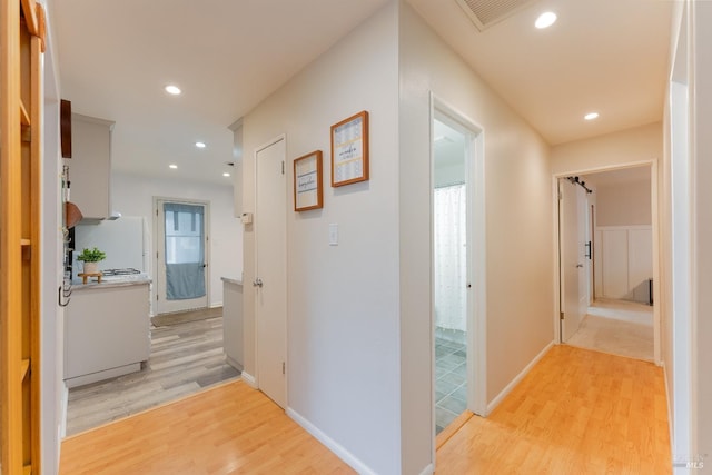 hallway with recessed lighting, visible vents, light wood-style flooring, and baseboards