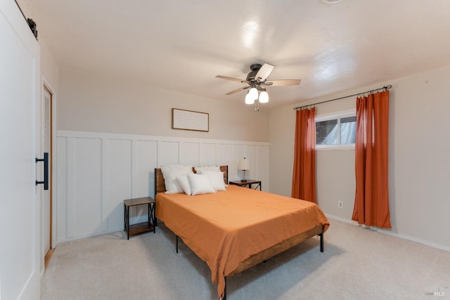 bedroom with wainscoting, light colored carpet, and ceiling fan