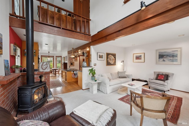 living room featuring a wood stove, light wood-style floors, a towering ceiling, and light carpet