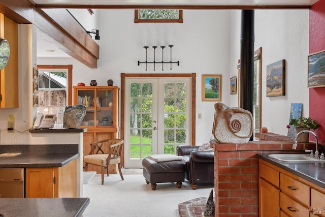 kitchen featuring dark countertops, a healthy amount of sunlight, light carpet, and a sink