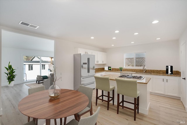 kitchen featuring refrigerator with ice dispenser, sink, light stone counters, white cabinets, and stainless steel gas cooktop