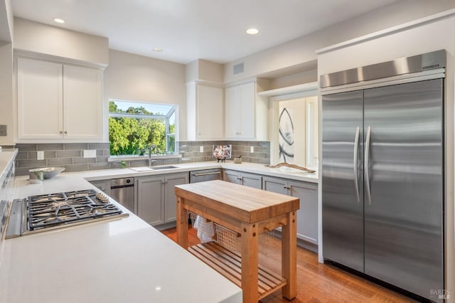 kitchen featuring stainless steel appliances, white cabinets, light countertops, and a sink