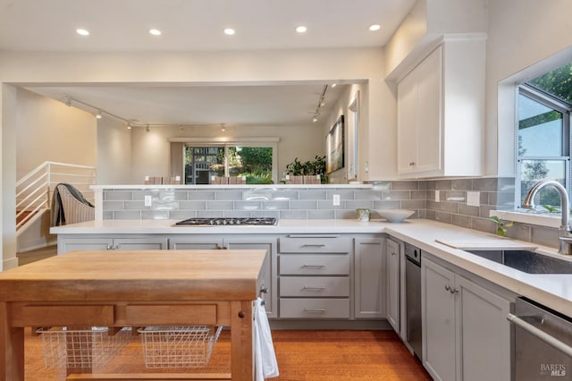 kitchen with light countertops, appliances with stainless steel finishes, a sink, and decorative backsplash