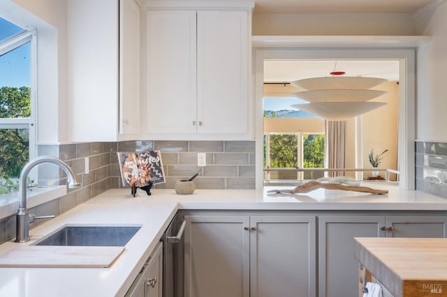 kitchen featuring light countertops, tasteful backsplash, a sink, and white cabinetry