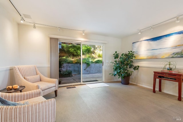 living area with light carpet, a wainscoted wall, visible vents, and track lighting