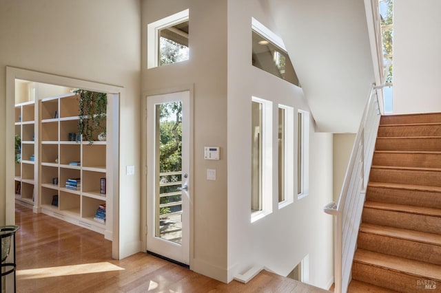 entrance foyer featuring a towering ceiling, stairs, and wood finished floors