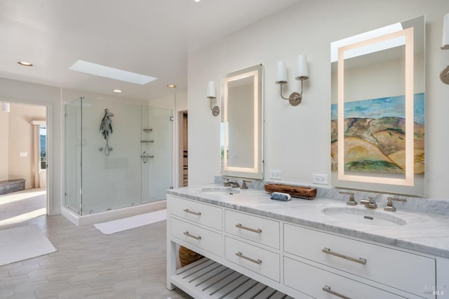 full bath with double vanity, a skylight, a sink, and a shower stall