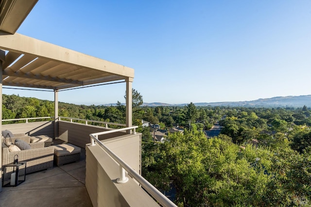 balcony with a mountain view, an outdoor living space, and a view of trees