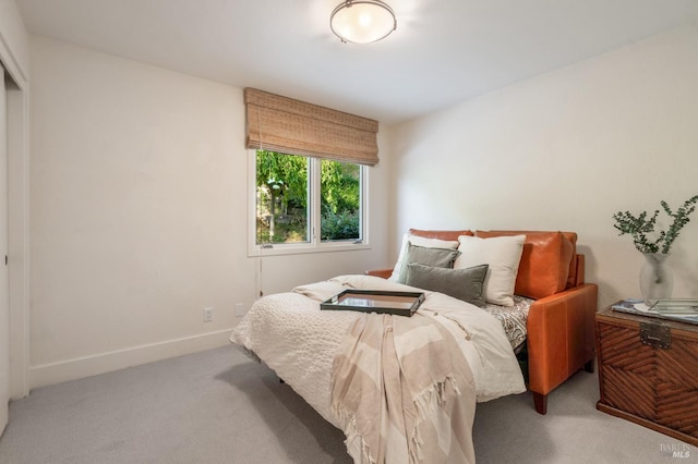 bedroom featuring light carpet and baseboards