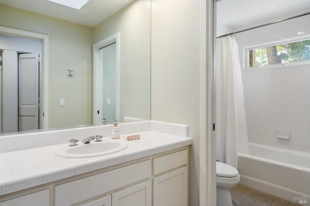 full bathroom featuring toilet, a skylight, shower / tub combo with curtain, and vanity