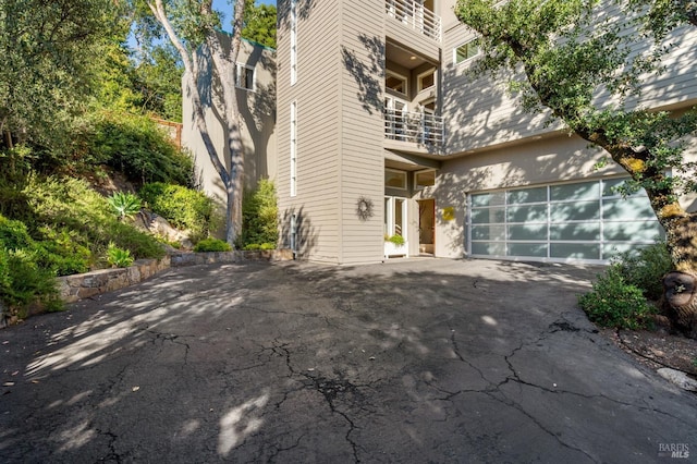 view of front of home featuring a garage, driveway, and a balcony