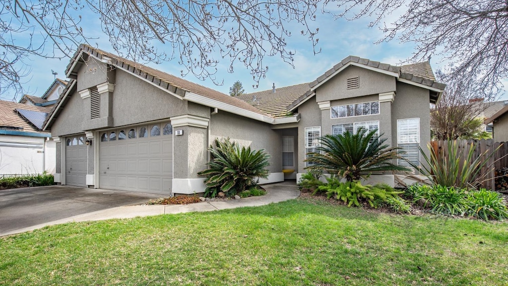 view of front of house with a front lawn, fence, concrete driveway, stucco siding, and a garage