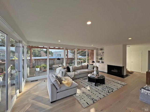 living room featuring light hardwood / wood-style flooring and a large fireplace