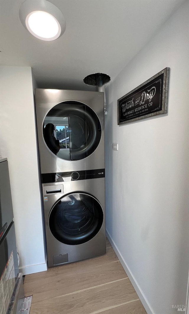 laundry room featuring stacked washer / dryer and light wood-type flooring