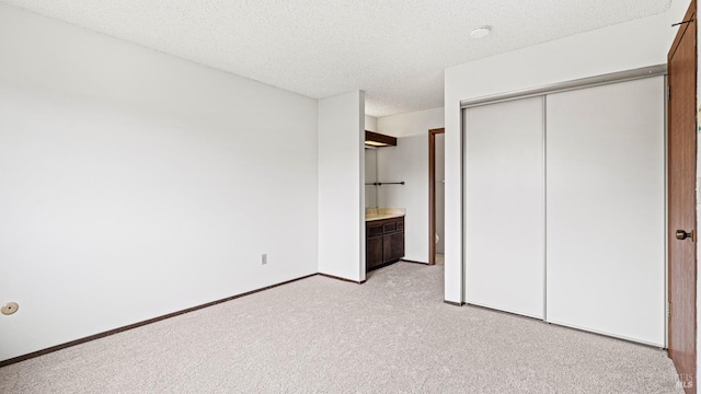 unfurnished bedroom with a closet, light carpet, and a textured ceiling