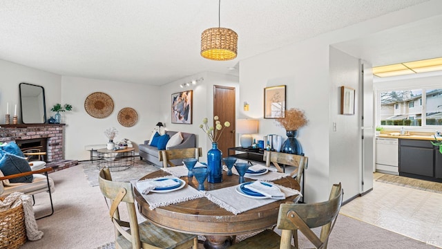 dining space with a brick fireplace, light carpet, and a textured ceiling