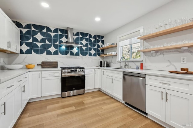 kitchen with white cabinetry, appliances with stainless steel finishes, sink, and wall chimney exhaust hood