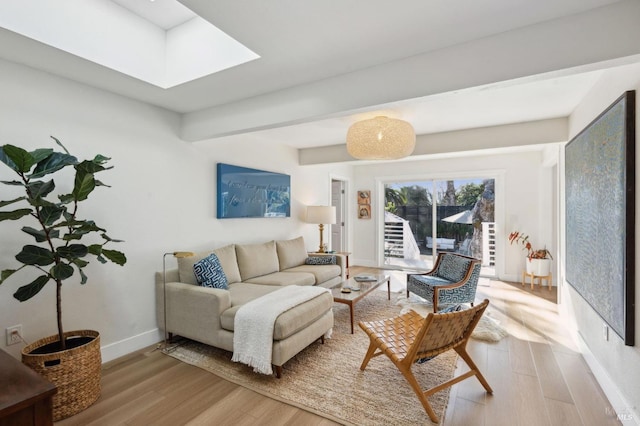 living room featuring light hardwood / wood-style floors, a skylight, and beam ceiling