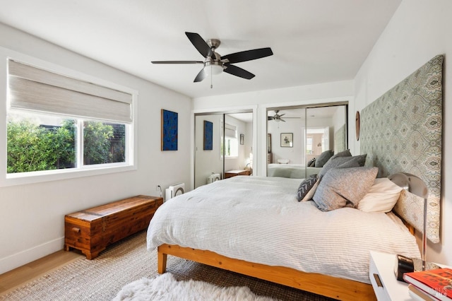 bedroom with hardwood / wood-style floors, two closets, and ceiling fan