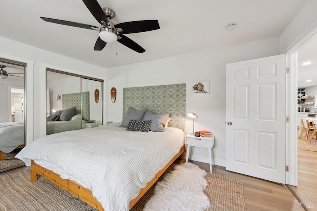 bedroom with multiple closets, ceiling fan, and light hardwood / wood-style flooring