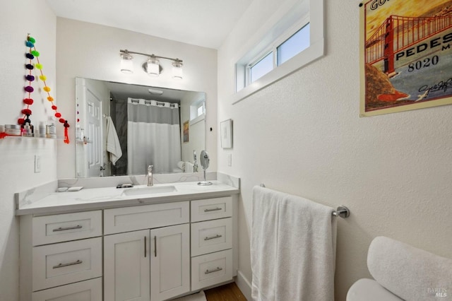 bathroom with toilet, vanity, and a shower with shower curtain