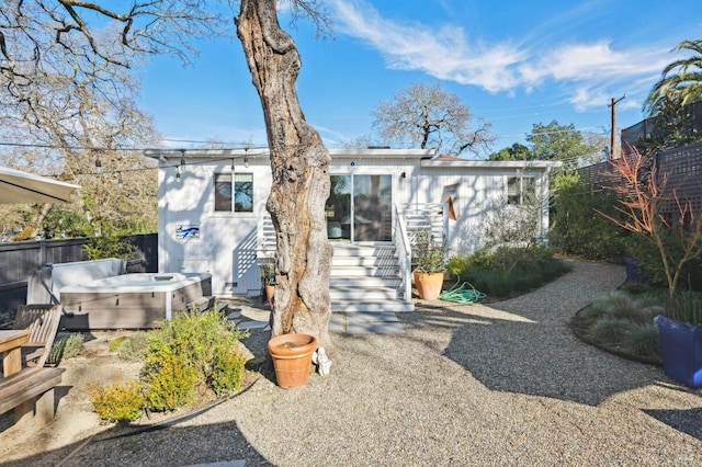 rear view of property with a hot tub