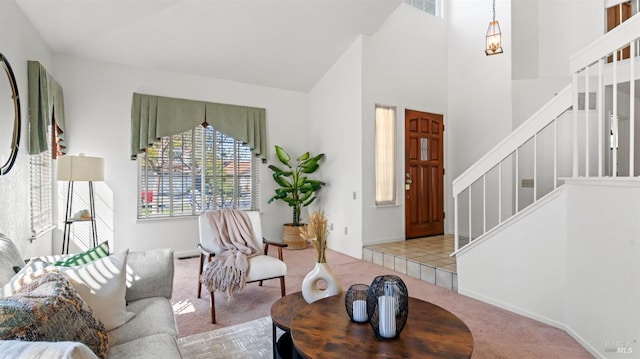 living area featuring carpet, visible vents, stairway, and a high ceiling