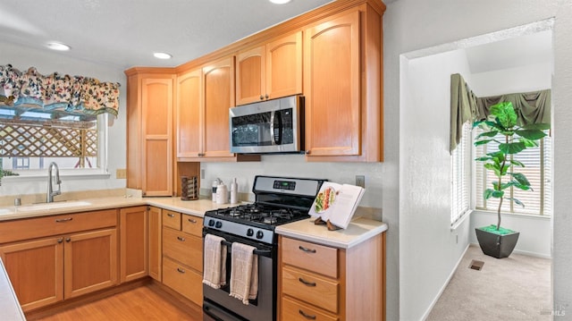 kitchen with stainless steel appliances, recessed lighting, light countertops, a sink, and baseboards