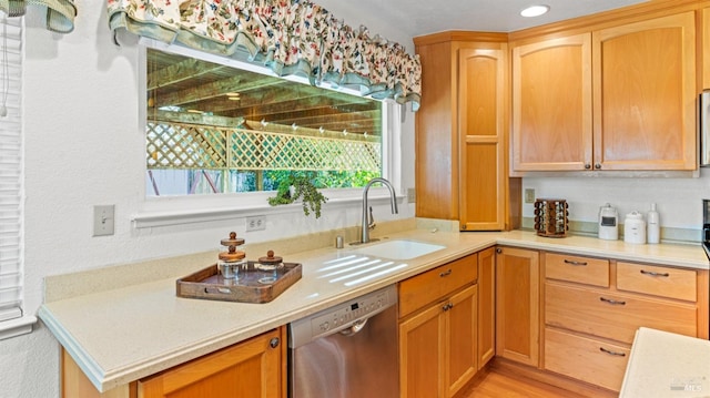 kitchen with a sink, light wood-style flooring, light countertops, and stainless steel dishwasher