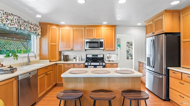 kitchen featuring light countertops, appliances with stainless steel finishes, a breakfast bar area, and a sink