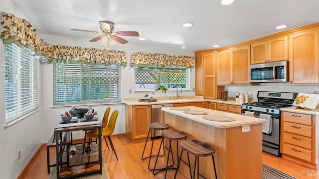 kitchen featuring light wood-style flooring, a kitchen island, stainless steel appliances, and light countertops