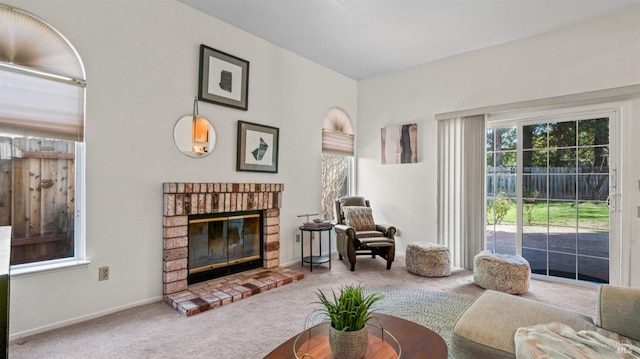 sitting room with a brick fireplace, carpet flooring, and baseboards