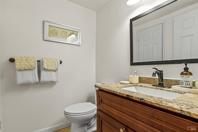 bathroom with vanity, toilet, and baseboards