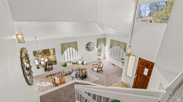 stairs with carpet floors, an inviting chandelier, and visible vents