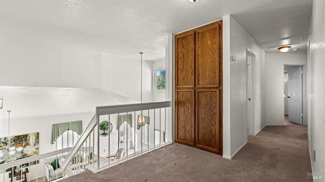 hall with a chandelier, a textured ceiling, carpet flooring, and baseboards