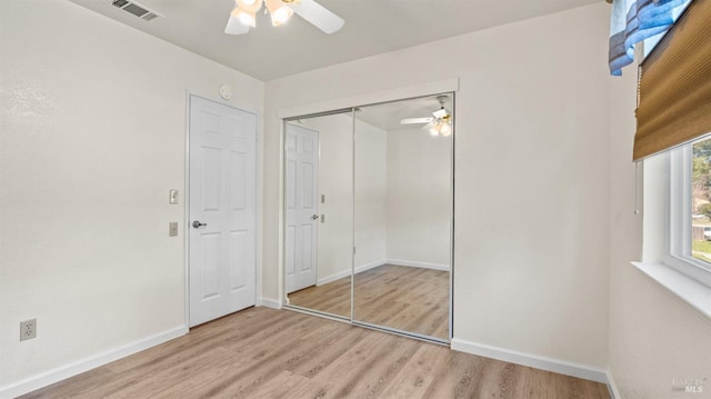 unfurnished bedroom featuring ceiling fan, wood finished floors, visible vents, baseboards, and a closet