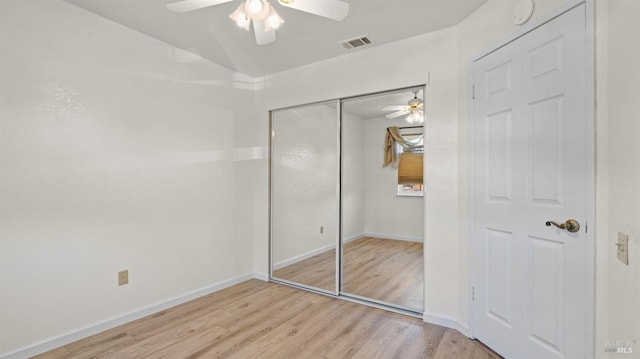 unfurnished bedroom featuring baseboards, visible vents, a ceiling fan, wood finished floors, and a closet