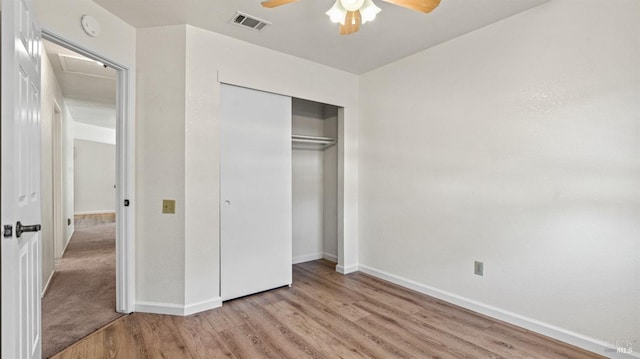 unfurnished bedroom with a closet, wood finished floors, visible vents, and baseboards