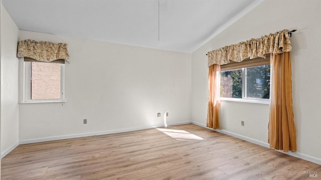 empty room featuring light wood-type flooring, baseboards, and lofted ceiling