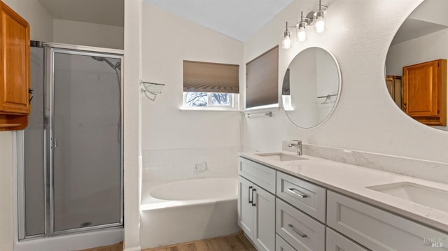 full bathroom featuring a stall shower, a garden tub, a sink, and double vanity