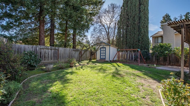 view of yard featuring a playground, a storage unit, an outdoor structure, and a fenced backyard