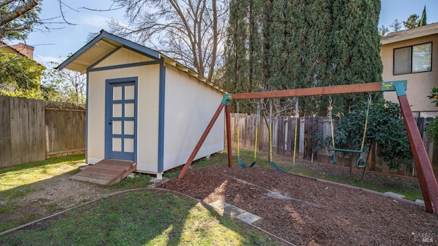 view of shed with a playground and a fenced backyard