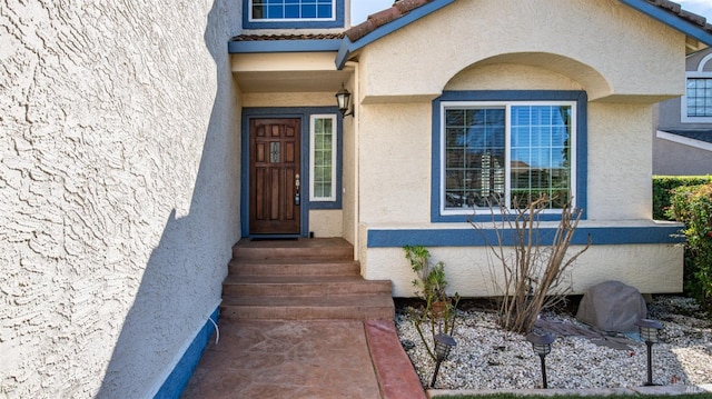 entrance to property featuring a tiled roof and stucco siding