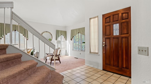 foyer entrance with light carpet, light tile patterned floors, baseboards, and stairway