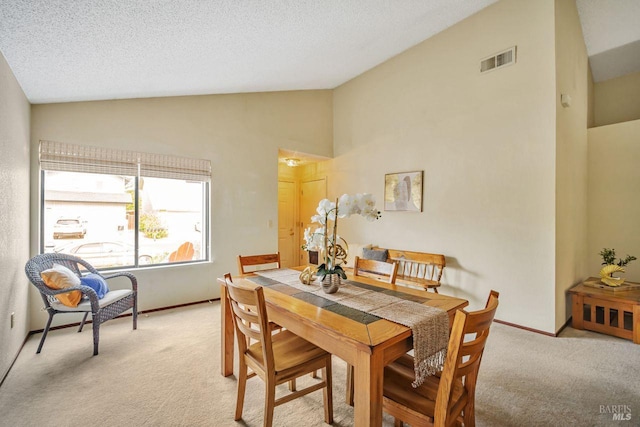 dining space featuring lofted ceiling, light carpet, visible vents, and a textured ceiling