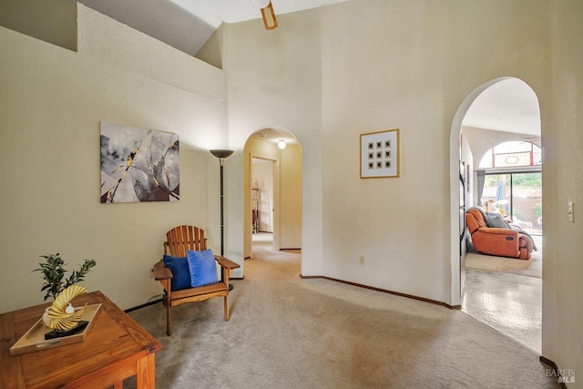 living area featuring high vaulted ceiling, baseboards, arched walkways, and carpet flooring