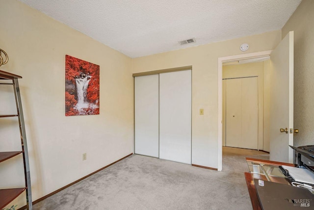 unfurnished bedroom with baseboards, visible vents, carpet, a textured ceiling, and a closet