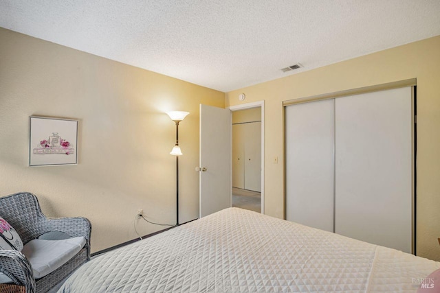 bedroom with a textured ceiling, visible vents, and a closet